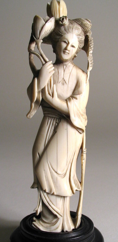 DESCRIPTION: A lovely ivory figure of a Chinese maiden in flowing robes holding a flower in her right hand, along with sheaves of grain which wrap around the back of her head and fall on the opposite shoulder.  Very good condition. DIMENSIONS:  Ivory is 6” high (15.2 cm); 6 ½” high (16.5 cm) including stand. <div id='rater_target1068469'></div>
