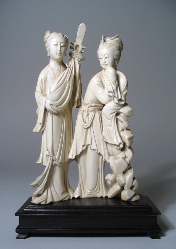 DESCRIPTION:  A Chinese ivory carving of two lovely maidens, one holding a musical instrument protected in a cloth bag, the other leaning on a rock wall with a bird ornament in her hair.  Very good condition, no repairs or losses. The age is seen from the darker back side which has had less light exposure; dating from latter Qing Dynasty, 1890 - 1910.  DIMENSIONS: 8” high including rectangular stand; 6 ¾” high without stand.  Stand is 5” long (12.7 cm). <div id='rater_target1119547'></div>
