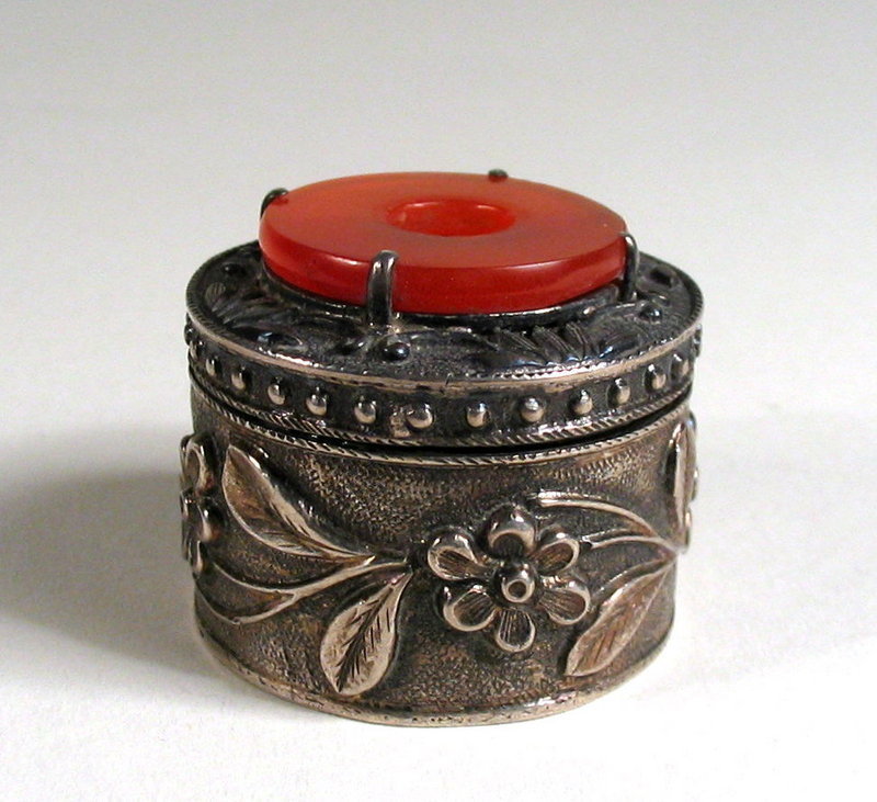 DESCRIPTION:  An attractive, round Chinese silver export pill box, banded with repossee’ floral designs, the hinged lid crowned with a carnelian disc.  On the base is stamped, “MADE IN CHINA NO 28 SILVER.”  Dating from the early 20th C., this little antique box is in excellent condition. DIMENSIONS:  1 1/8” diameter (2.8 cm) x 1” high (2.5 cm).<div id='rater_target1127515'></div>

