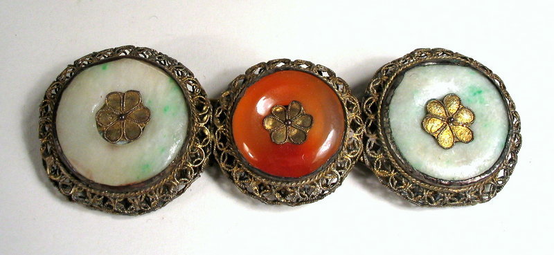 DESCRIPTION:  A Chinese export filigree bar pin fashioned from three hardstone discs, two of jade and one carnelian, mounted in delicate, decorative openwork made from thin twisted wire.  Most likely dating to the Victorian era (1837 – 1901) when such pins were fashionably worn at the neck fastening two collars, the pin is in very good condition with no chips to the stones and slight wear to the wirework.  DIMENSIONS:  3 ¾” long (9.5 cm) x 1 3/8” wide (3.5 cm).<div id='rater_target1132083'></div>
