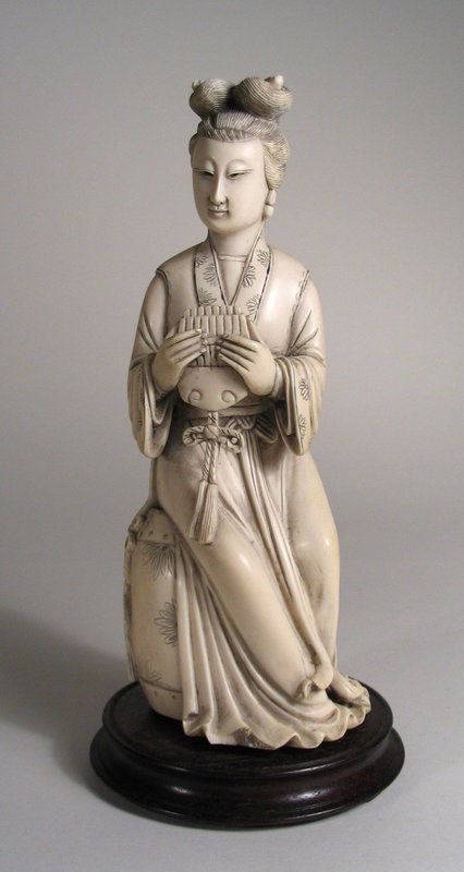 DESCRIPTION:  A fine Chinese ivory carving of a seated female musician, her hair pulled up in a double chignon. Her beautiful face gazes downward while holding her tasseled instrument with both hands.  She is seated on a decorated drum, the back of which bears an inscription. Early 20th C.  PROVENANCE: The Collection of G. Jules Marder, past president of the Oriental Art Club of Chicago. DIMENSIONS: 8 ¼” high (21 cm) without wood base; with base, 9” high (23 cm).<div id='rater_target1152615'></div>
