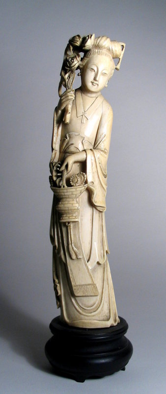 DESCRIPTION:  A tall Chinese antique ivory carving of a beautiful maiden with flowers.  Dressed in flowing robes, she holds a basket of chrysanthemums in her left hand, and her raised right hand holds a large bouquet of roses, complementing her serene face and coiffed hair. Excellent condition.  DIMENSIONS: 12 ¼” tall without stand (31 cm); 14 ½” tall with stand (37 cm).<div id='rater_target1173712'></div>
