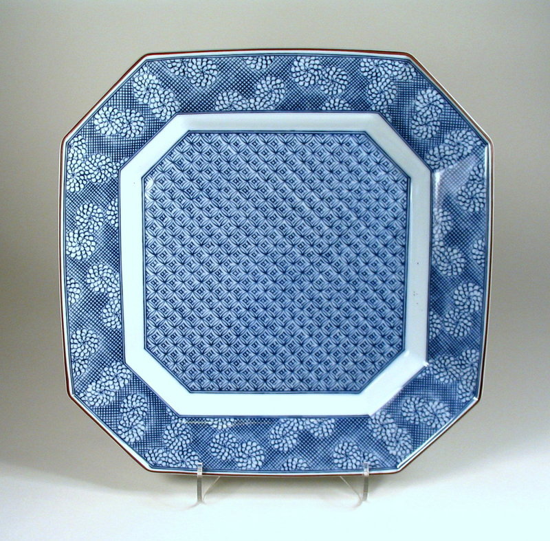 DESCRIPTION:  This vintage eight-sided Japanese platter is raised on a square foot with blue underglazed geometric designs covering the flat interior and with chrysanthemums scattered over diagonal cross hatching around the raised edges.  Perfect condition with no chips, cracks or repairs, and dating to the first half of the 1900’s; maker’s mark and collector’s stickers are on the back.  DIMENSIONS:  10 ¾” square (27.4 cm) x 1 5/8” high (4.1 cm). <div id='rater_target1190316'></div>
