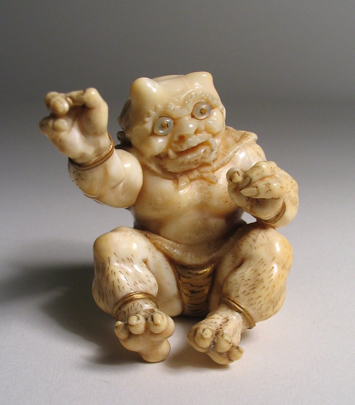 DESCRIPTION:  A well carved Japanese ivory okimono of a seated, three-clawed oni with arms outstretched and lacquered gold bracelets on each wrist and ankle.  His eyes are double inlaid with abalone shell and when turned over we see his lacquered, tiger-striped loin cloth.  Very appealing and dating from the Meji Period, 19th C.  DIMENSIONS:   2" high (5 cm) x 2 1/4" wide (5.8 cm).  <div id='rater_target1239565'></div>
