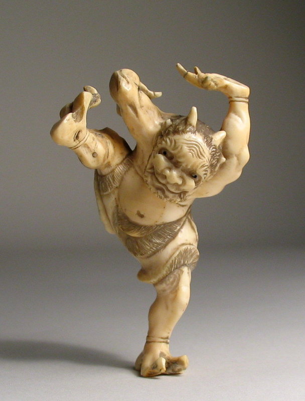 DESCRIPTION:  A unique Japanese ivory okimono of a mischievous bearded oni, carved to be in perfect balance as he performs several acrobatic poses.  The skill and planning of the carver is evident as the two-horned oni goes from balancing on one leg, to one hand, to a seated position.  Also imbued by the carver is wonderful animation and detail in the oni's face, muscular back and arms, and the oni's fur loin cloth.  Dating from the Meiji Period (1868 - 1912), this okimono is in good condition with probable old repair to fingers on one hand.  DIMENSIONS:  When seated, 3" long (7.6 cm) x 1 3/4" high (4.5 cm). <div id='rater_target1251535'></div>

