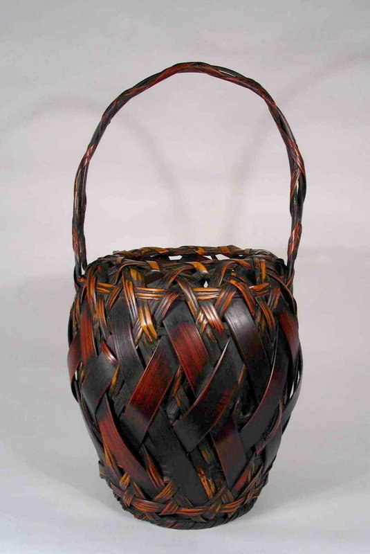 DESCRIPTION:  A fine smoked bamboo ikebana basket woven in a tall ovoid form with entwined bamboo handle.  The basket is crafted with a vertical diagonal weave from both wide and narrow splints in contrasting colors.  This sturdy and handsome basket has a beautiful aged patina with no losses detected; early 20th century.  DIMENSIONS:  18 ½” high x 8 ¾” diameter.  <div id='rater_target1270134'></div>
