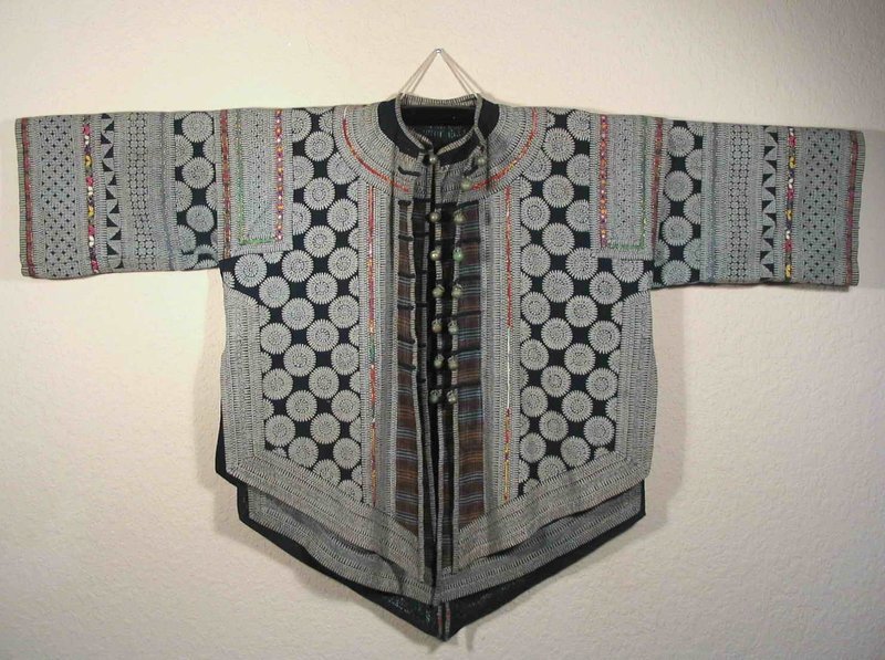 DESCRIPTION:  A fine two piece batik jacket and matching vest by the ethnic minority tribe “Ge,” a subgroup of the Miao culture.  The Ge people live along the banks of the Chong-an-jiang River in Guizhou Province and are superlative batik artisans.  
<p>For this labor intensive creation, hot wax was applied to the thick cloth in geometric designs consisting of a background of “wheels” edged in wide linear borders. The cloth was then dyed in indigo, dried, and the wax melted and washed out to leave the design in white on a dark blue background.  Brightly colored woven trim edged with gold thread has been appliquéd onto the vest and jacket, along with bands of plaid fabric.  Both garments are finished with round, pewter-like buttons (no missing buttons).  Photos show the garments both together and separately.
<p>This ensemble is very wearable, and the two pieces can be worn separately, together, or hung as beautiful textile art.  Photos don't do justice to this extraordinary hand-made textile.  Excellent condition with no holes, stains or tears; between 40 to 50 years old.  DIMENSIONS:  The size is equivalent to adult medium:  51” from sleeve to sleeve (1.3 m) x 29” long (74 cm) x 25” across underarms (50” chest or 1.27 m). 
<div id='rater_target1290310'></div>
