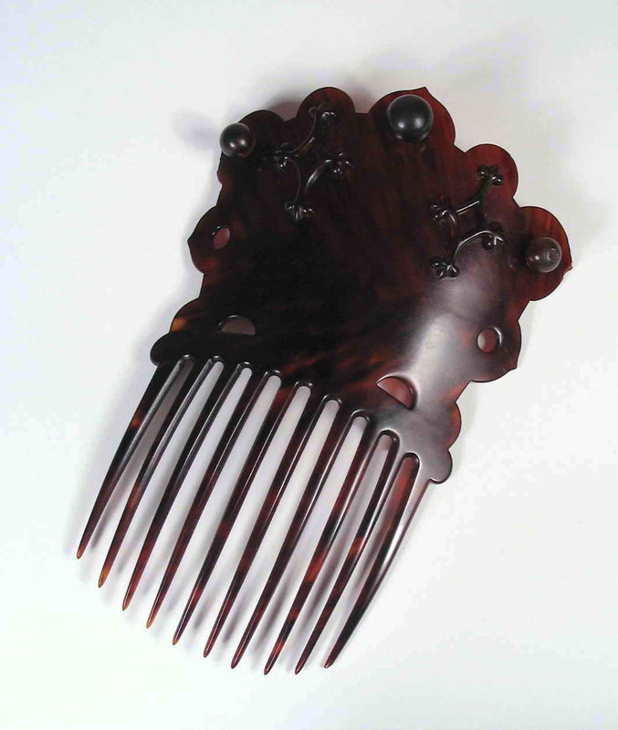 DESCRIPTION:  A large, ten pronged tortoise shell comb made for the European market (Victorian era, circa 1880-1890).  The fashion of the day included large elaborate combs placed in upswept hair, and this one is a real beauty!  The curved prongs and scalloped crown are from a single piece of shell which is mounted with three large round beads and two carved triangular designs. Very good condition with only a couple of tiny nits that are difficult to even see.  DIMENSIONS:  6 ½” long (16.5 cm) x 4 ¼” wide (11 cm).  <div id='rater_target1291926'></div>
