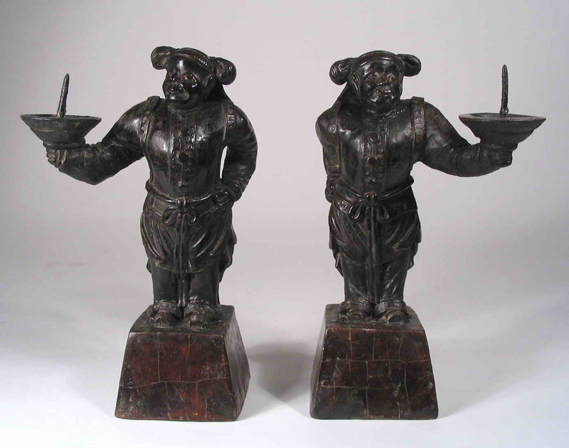 for the Pair<br /><br />
DESCRIPTION: A captivating pair of lacquered figural candle pricks, each in the form of a smiling attendant with hand on hip, wearing a banded hat and holding aloft a candle dish.  The figures themselves are hand crafted of solid brown lacquer around a wire frame, while the flared bases are wood blocks covered in brown lacquer.  This unusual, rare pair date from approximately 1750 – 1850, and are in remarkable condition with the expected age wear to the lacquered surface.  DIMENSIONS: Each approximately 9” high (22.8 cm) x 5” wide (12.7 cm) including candle dish.  <div id='rater_target1292351'></div>
