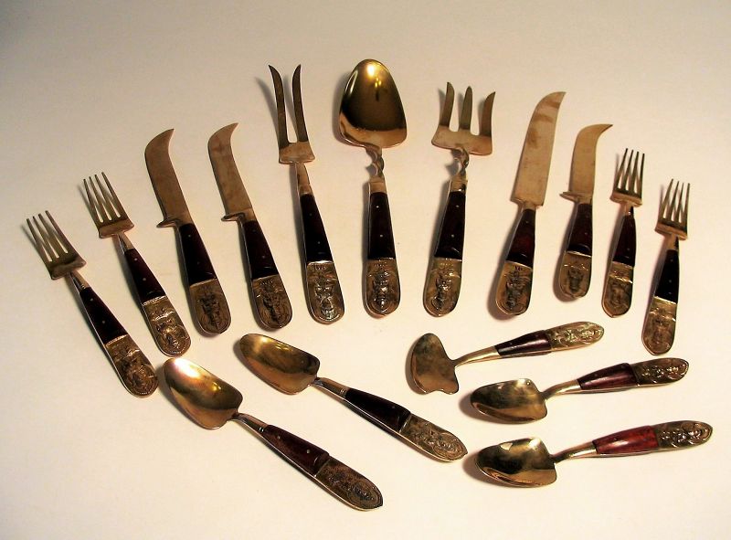 Set<br /><br />
DESCRIPTION: A complete 29-piece flatware / cutlery set, made in Thailand during the late 1940s to early 1950s.  Each utensil is shaped from solid brass and encased between rosewood slab handles, the tips of each with a raised brass figure in court dress and “Siam” stamped at the base.  The set consists of dining or dessert cutlery for 8 people (knives, forks & spoons), plus a serving fork & spoon, sugar spoon, and a carving set. Original wood storage box with emerald velvet lining is included. A ribbon on an interior corner is stamped: “TKC, 140 Phosri Road, Thailand.” Very good condition. DIMENSIONS: Box is 13” x 13” x 2.75.”
<div id='rater_target1372916'></div>
