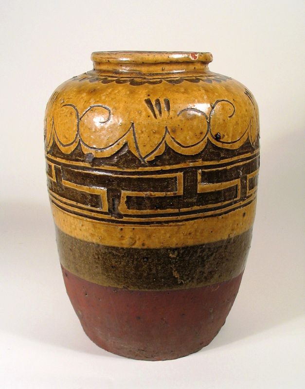 DESCRIPTION: Long acknowledged as masters of porcelain, the Chinese also excelled at pottery making. Qing Dynasty domestic pottery used regional clays and showed distinctive regional styles. This pottery, used for the storage of oil and other household goods, exhibited tremendous, quiet beauty as well as utility. Crafted of red clay and originating from Jiangxi Provence, this handsome jar is an excellent example with its incised geometric decorations in two-toned brown and yellow ochre glazes. Dating to the late 19th C, it is in excellent condition with minor scuffs to the glaze around the rim and original firing flaws produced in the kilns. To see another companion piece, go to our listing #GD38. DIMENSIONS: 7 ½” diameter (19 cm) x 10 ½” high (26.7 cm).   
<div id='rater_target1373192'></div>
