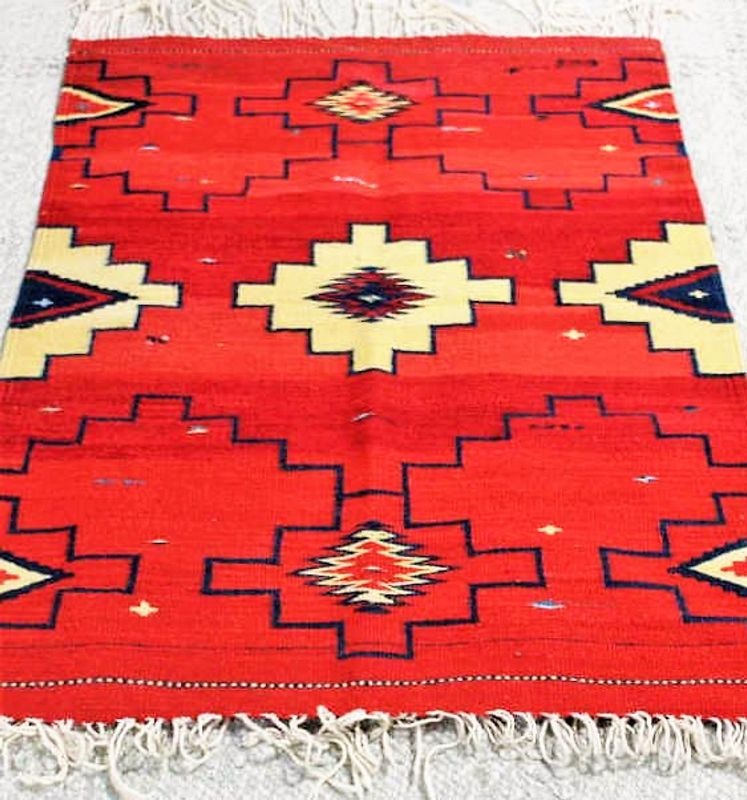 DESCRIPTION: A hand woven flat weave Mexican wool carpet, dating from the mid 20th C, with bright red ground and geometric designs in dark blue and light beige.  Originally purchased in Mexico in the 1970’s by an interior designer who stored it for decades, this rug is in like-new condition. From a Scarsdale, NY Estate; rug is reversible. DIMENSIONS: 34” wide x 53” long, plus fringe.
<div id='rater_target1394022'></div>
