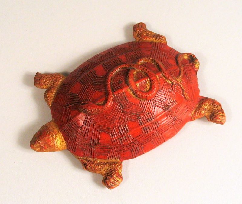 DESCRIPTION: A red and gilt ink cake in the form of a turtle with a curled snake on its back. In ancient China, the tortoise and the snake were thought to be spiritual creatures symbolizing longevity. Both the front and back have been finely pressed in raised relief with gilt accents. One of the treasures of the Chinese scholar’s studio, this ink cake is in excellent condition, in its original box, and dates from the first quarter of the 20th C. or earlier. DIMENSIONS: 3” long (7.7 cm).   
<div id='rater_target1394604'></div>

