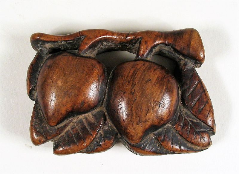 DESCRIPTION: A nice old Chinese toggle carved from a striated wood in the form of two peaches. The peach is a symbol of longevity, and this thick toggle has a wonderful aged patina that only comes from age and handling. Strung with a cord through the holes under the stems, it would have hung from a sash and been used as a counterweight to a tobacco pouch or other utilitarian object. A wonderful example of Chinese folk art, this toggle dates from the 1700’s. DIMENSIONS: 2 ½” wide (6.4 cm) x 1 ¾” high (4.5 cm).   

<div id='rater_target1397377'></div>

