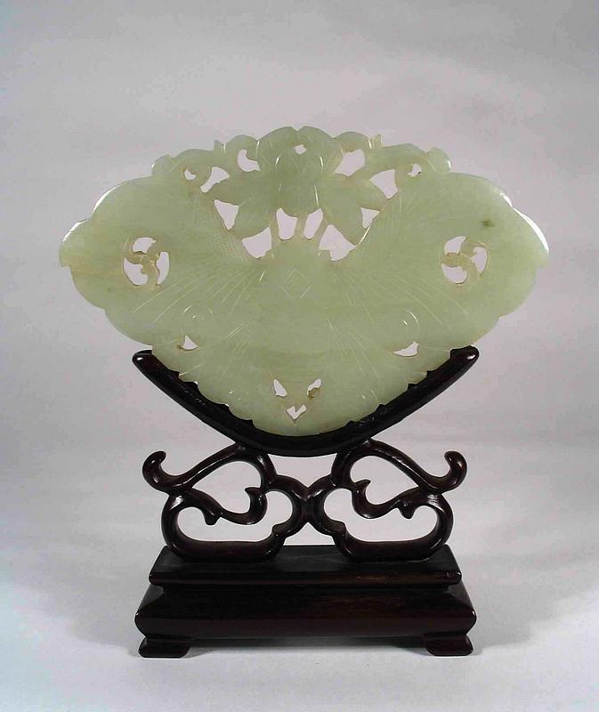 DESCRIPTION:  A larger sized celadon colored jade (nephrite) plaque in the form of a butterfly (or moth) with stand.  At the butterfly’s head is a pierced flower with leaves. In Chinese iconography, when a butterfly and plum blossoms appear together, it symbolizes long life and immaculate beauty.  This is perhaps the motif found in this carving.  From the collection of a retired Washington D.C. judge, Qing Dynasty, pre 1900’s.  The jade is in excellent condition; the stand has a repair to one arm.  DIMENSIONS:  Jade is 5 5/8” wide x 3 5/8” high.  On stand, 6 ¼” high.<div id='rater_target466477'></div>
