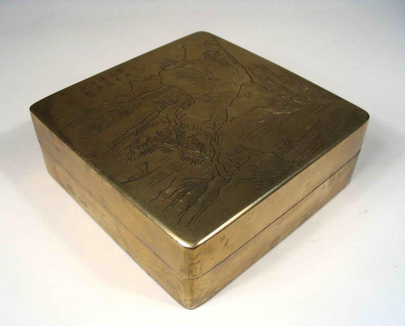DESCRIPTION:  A unique scholar’s calligraphy box of solid brass that includes an ink stone within the inner lid.  The outer lid has a ten-character Chinese inscription at the top, and shows an idyllic scene with mountains, pavilions, boats, and trees in finely hand-incised lines.  Inside this lid is a thin, square ink stone surface held in place by an inner rim.  A nice portable way to carry necessary writing accoutrements, the lower portion of the box was used to hold ink cakes and is lined with copper.  This box has a nice hefty weight to it with its original patina, and has obviously been used for its intended purpose, with the interior covered in black ink.  Estimated to date from the first quarter of the 20th century, it would be make a handsome addition to any scholar’s art collection.  DIMENSIONS:  Approximately 3 ¾” square (9.5 cm) x 1 ¼” high (3.25 cm).<div id='rater_target545698'></div>

