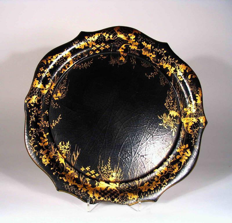 DESCRIPTION:  A beautiful Victorian black lacquer papier-mache Chinoiserie tray in circular form with scalloped edges and gilt floral designs.  This can be purchased with a companion piece, our listing BPB189, both shown together in the last photo for size comparison.  Mid 19th C. with a lovely, aged crackled finish to the lacquer; chip on one edge as shown in photo. DIMENSIONS:  12 ½” diameter (31.5 cm).<div id='rater_target559201'></div>
