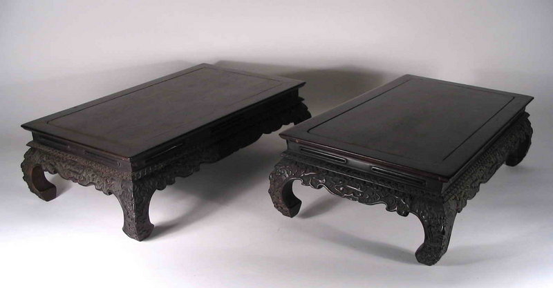 for the Pair<br /><br />
DESCRIPTION:  A matched pair of rare and exquisitely carved rectangular zitan display stands in kang table style.  These museum quality stands are constructed with panel tops and ice-plate edges upon inset, pierced waists. The upper aprons display a narrow, relief carved leaf diaper pattern; the lower aprons are widely flared and scrolled, carved in high relief with a flourishing cloud design. The outwardly bulging legs are similarly carved with taotie masks at each knee ending with in-turned horse-hoof feet.  
<p>Rarely do such fine zitan pieces come to the market, and these are consigned from a long held private Florida collection. Both are in very good condition with no warping, and each with minor shrinkage to one side of the panel tops. The beautiful zitan wood ranges from dark burgundy to black in color and they date from 19th C., Qing Dynasty.  DIMENSIONS:  Each 16 ½” long (42 cm) x 9 ½” wide (24 cm) x 4 ¾” high (12 cm).
<div id='rater_target844126'></div>

