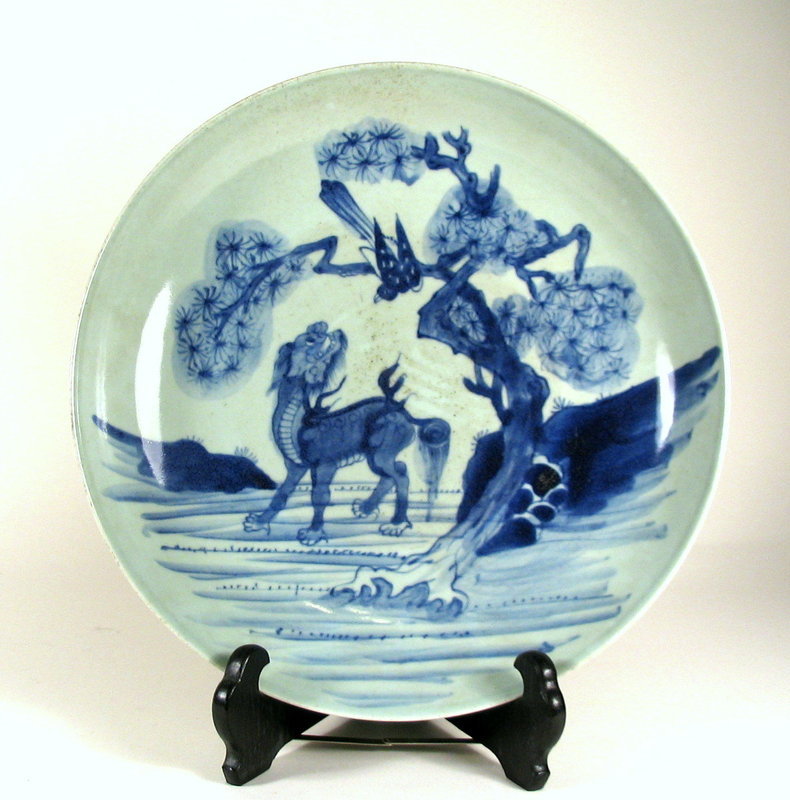DESCRIPTION:  A large antique porcelain plate, well decorated with a mythical Kylin gazing upward at a large bird perched in a pine tree.  The decoration is in underglazed blue with a clear glaze containing a faint blue tint.  The base is unglazed and unmarked showing the finely grained paste. Excellent condition, no chips, cracks or repairs; wood stand not included. DIMENSIONS: 11 1/4” diameter (28.5 cm) x 2  1/8" high (5.4 cm). <div id='rater_target1214637'></div>
