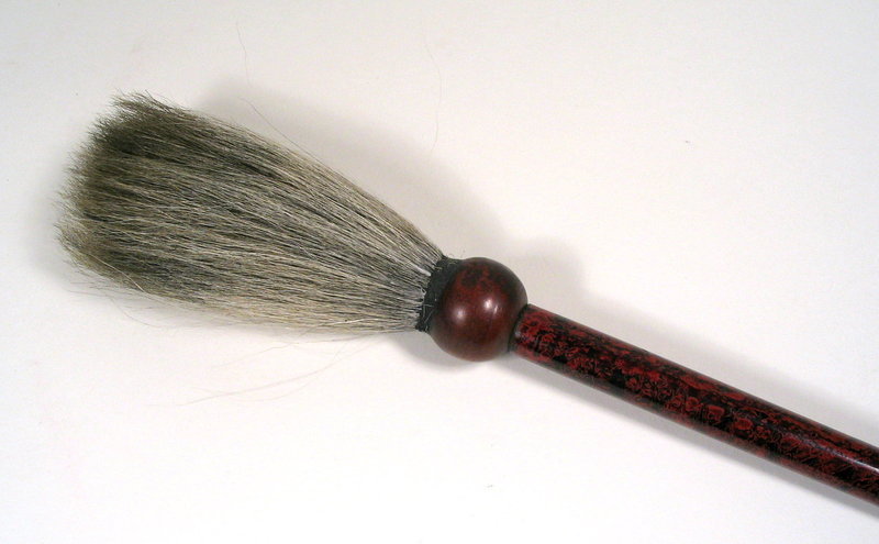 DESCRIPTION:  A handsome scholar's calligraphy brush, crafted from a wood shaft that has been beautifully lacquered in a swirling, wave-like pattern of red and black lacquer.  The lacquer shaft is connected to the natural bristle brush by a bulbous wood ferrule.  One of the four treasures of the scholar’s studio, this striking scholar’s brush would have made an attractive companion to a fine brush pot.  Very good condition; most likely dating from 1900 - 1930.  DIMENSIONS:  15 1/2" long (39.5 cm). <div id='rater_target1236955'></div>

