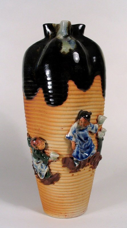 DESCRIPTION:  A large and handsome Sumida Gawa vase with ribbed body, high relief figures and pinched neck.  A thick, traditional flambe' glaze in dark brown and blue covers the mouth and neck, and flows down the shoulders.  Fine attention to detail has been paid to the handmade figures of a boy and girl standing on ledges against the ribbed body.   Inoue (Ryosai) maker's mark in pear-shaped appliqué on the back.  Early 20th C. (pre WWII) and in perfect condition; no chips or repairs.  DIMENSIONS:   12 1/2" high (31.8 cm) x 5 1/2" diameter (14 cm).  <div id='rater_target1265593'></div>

