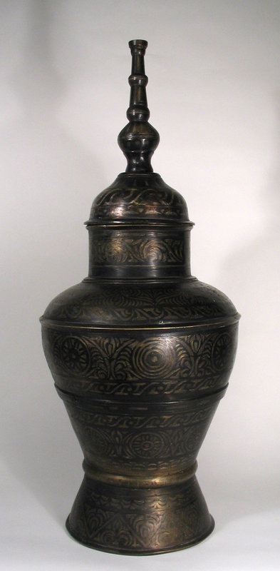 DESCRIPTION:  A large, heavily cast bronze storage vessel (gadur), with brass and silver inlays crafted by the Maranao tribe of the Phillippines.  The round body and flared foot are profusely decorated with inlaid floral and geometric designs; the body is topped with an inlaid domed lid and tall spire. From the estate of Asian art collector, Dr. Edward Gerber.  CONDITION:  This is a fairly early example, dating from the late 1700's to early 1800's, and shows usage wear, some pitting, and a couple of very old repairs.  DIMENSIONS:  31 1/2" high (80 cm) x 12 1/2" diameter; 22 lbs.

<p>CULTURAL BACKGROUND:  This distinctive type of metalwork is made by people of the Maranao tribe who live on Mindanao Island in the southern Philippines.  The Maranao people have lived on the island of Mindanao since at least the 13th century, and are highly acclaimed for their distinctive artwork, sophisticated weaving, wood carving, and intricate metal crafts.  They share in a generalized Southeast Asian culture but also have their own cultural identity. "Maranao" means "people of the lake" referring to Lake Lanao (province of Lanao del Sur), the area where most have lived for hundreds of years.
<div id='rater_target1266620'></div>
