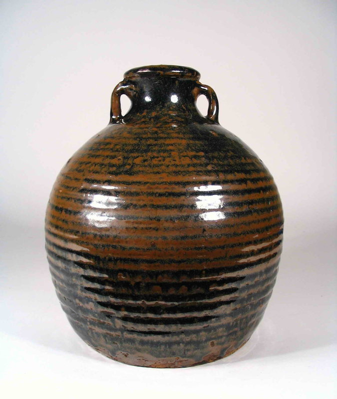 DESCRIPTION: A Jin Dynasty (1115-1234 AD) pot / container decorated with a luscious, thick black and brown glaze over a bulbous, ribbed body.  Two strap handles are attached to both sides of the short neck below the flared rim.  Overall very good condition with small repair to rim. DIMENSIONS: 9 ½” high (24 cm) x 8 1/2” diameter (21.5 cm).<div id='rater_target1274491'></div>
