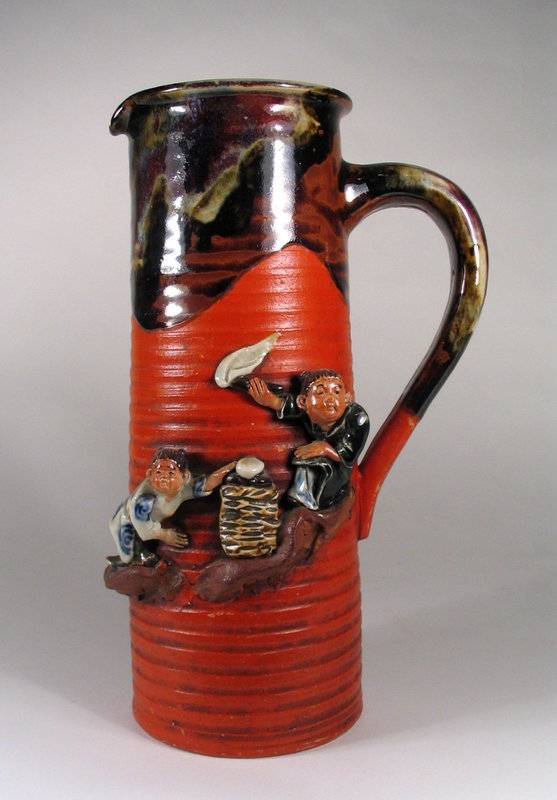 DESCRIPTION:  A large and attractive Sumida Gawa tankard with a red ribbed body, graceful handle, and high relief figures of two children.  A traditional flowing flambe' glaze in dark brown and beige coats the top third of the mouth and handle.  Fine attention to detail has been paid to the handmade figures of children standing on ledges against the ribbed, cold painted body.  On the back in blue characters is the potter's mark of Inque Ryosai, a family of three generations of potters who made Sumida wares at the family kiln in Yokohama.  Early 20th C. and in perfect condition; no chips or repairs.  DIMENSIONS: 12" high (30.5 cm) x 7" wide (17.8 cm). <div id='rater_target1276399'></div>
