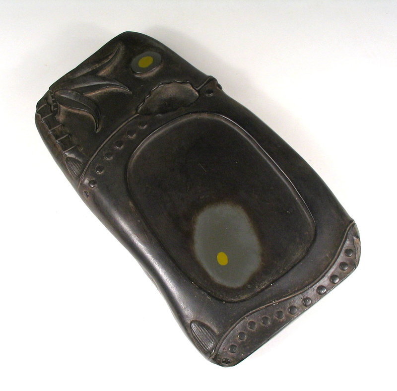 DESCRIPTION:  A fine 19th C. Chinese ink stone, crisply carved in the form of a bamboo node with leaves at the top and root knobs at the bottom.  A deep water well has been carved into the upper section.  Natural inclusions, called "eyes," are highlighted within the duan stone's design, with one eye at the top carved to simulate the moon, and the other incorporated into the stone's grinding surface.   
<p> ABOUT DUAN INK STONES:  One of the four treasures of the Chinese scholar's studio, the ink stone was revered as the soul of the scholar's implements.  Duan stone is a favored stone for making ink slabs in China and is so named because the Duanxi River runs at the foot of Mount Fuke, where the stone is found.  Said to be the best stone for making ink slabs, the stone is hard, fine and even in texture. Its surface allows ink to be easily ground, and the ink does not dry quickly 
<p>CONDITION:  One small chip at the right bottom corner; beautiful surface with a nice, hefty weight.   DIMENSIONS: 8" long (20.3 cm) x 4 1/2" wide (11.5 cm) x 1 1/4" thick (3.2 cm). 
<div id='rater_target1279083'></div>

