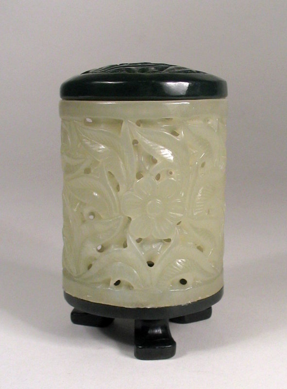 DESCRIPTION:  A well carved cylindrical jade cricket box, the body carved and pierced from white jade in a leaf and flower pattern, with a dark cyan colored jade lid, pierced and carved in the same pattern.  The box is raised on an ebony stand with three feet.  Dating from the first half of the 20th C., this cricket box is in excellent condition.  DIMENSIONS:  3 1/8" high (8 cm) x 2" diameter. 

<p>CULTURAL BACKGROUND: Keeping crickets is a tradition in China, with cricket boxes made in a variety of materials, shapes and sizes.  Crickets are kept as household or shop “pets,” admired for their chirping sound, or used in sport contests.  The more beautiful the box, the more prestigious the owner, and the more esteemed the cricket.  
<div id='rater_target1284962'></div>
