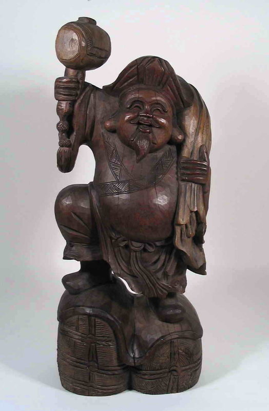 DESCRIPTION:  A large and delightful carved wood figure of one of the seven Japanese gods of good fortune, Daikoku, the deity of prosperity.  Here he is seen in his traditional pose, standing on two bales of rice with his wish-granting mallet in his right hand, and a bag of riches slung over his left shoulder.  Daikoku is also venerated as the deity of the kitchen where such carvings were traditionally displayed, sometimes in the ceiling rafters for good luck.  A wonderful mingei piece, his happy expression undoubtedly means he has good fortune awaiting the buyer!  In good condition with a few age fissures; Meiji Period, early 20th C.  DIMENSIONS:  24” high (61 cm) x 10” wide (25.4 cm) x 9 ¼” deep (23.5 cm).

<p>Mingei is a word meaning "arts of the people." It was coined by Dr. Soetsu Yanagi, through combining the Japanese words for all people (min) and art (gei). His keen eye observed that many useful, pre-industrial articles made by unknown craftsmen were of a beauty seldom equaled by artists of modern societies. This art shares a direct simplicity and reflects a joy in making, by hand, useful objects that are satisfying to the human spirit. 
<div id='rater_target1290985'></div>

