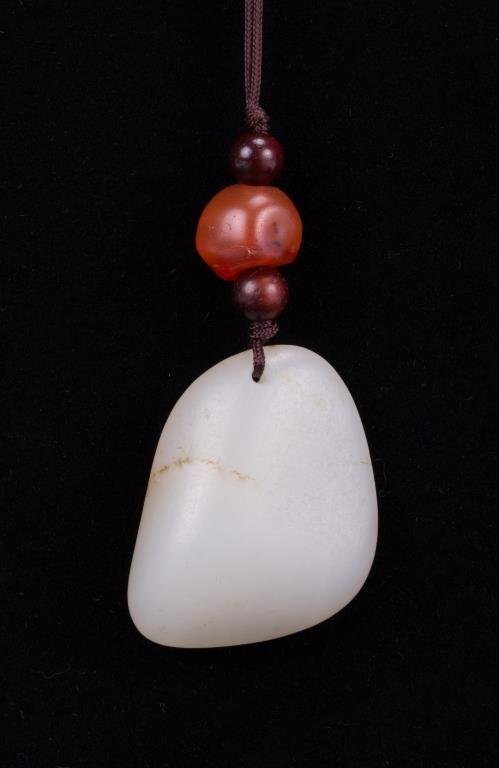 DESCRIPTION:  A lovely white jade toggle (or pendant) with scattered light brown to grayish inclusions, strung with an orange amber bead on a cord. This toggle dates from the Qing Dynasty and is in very good condition; the jade surface is quite smooth to the touch and there are no chips to the jade or amber bead.  DIMENSIONS:  Jade toggle: 1 1/4" long (3.2 cm) x 1" wide (2.5 cm).  <div id='rater_target1301236'></div>
