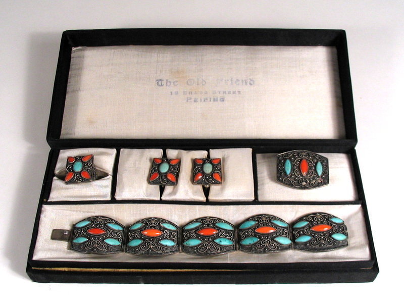 DESCRIPTION:  It's extremely rare to find a complete suite of matching antique Chinese jewelry; it's even more rare to find them in their original box.  This beautiful set consists of a matching silver filigree bracelet, a pair of earrings, a pin and a ring, all having natural turquoise and coral stones set between delicate scrolling silver wire work. The inside lid of the box is stamped, "The Old Friend, 18 Brass Street, Peiping."  Dating from the 1920's, the whole suite is in excellent condition with no losses or chips to the stones.  Each piece has a small silver plaque on the back reading, "SILVER/CHINA." DIMENSIONS:  Bracelet circumference when closed is 6.75" (17.2 cm, adult medium size).  The pin is 1.25" long (3.2 cm); ring and earrings are approximately .75" square (2 cm).  The ring is adjustable and the earrings have the original screw-type closures.  <div id='rater_target1303095'></div>
