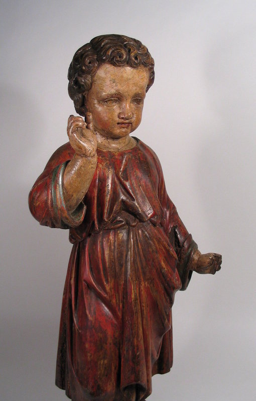 DESCRIPTION:  A fine Spanish Colonial carved wood figure (or santo) of the Christ Child.  This devotional sculpture was sensitively and realistically carved with the Christ Child standing, looking slightly downward with his right hand raised and wearing a draping red robe tied at the waist. Images such as these were created as objects of devotion, playing a significant role in introducing and educating indigenous peoples in the Americas to the Roman Catholic Church, which itself was an integral part of the Spanish colonization of the Americas.  This santo is quite early, dating from the late 17th C. CONDITION:  In remarkable condition considering its age; there are missing fingers on both hands, scattered insect damage (worm holes), a small number of age cracks (stable), and paint losses in various places. The whole is quite sturdy with a beautiful patina and inspirational presence. DIMENSIONS: Approximately 30" high (76.2 CM). <div id='rater_target1303965'></div>
