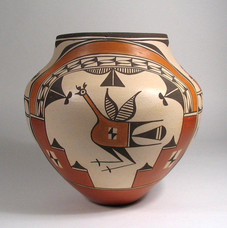 DESCRIPTION:  A large, hand coiled Zia Pueblo Olla by noted Zia potter, Elizabeth Medina.  This well formed pot has high shoulders tapering to a narrow foot, and is painted in four traditional Zia colors with natural sienna, burnt sienna and black designs on a white ground. The design is divided into four quadrants, two with lively, hopping roadrunners under rainbow arcs (a signature Zia design), and two with capped feather designs appearing as orange steps outlined in black with semi-circular black caps.  Arguably the best Zia potter today, this pot demonstrates Elizabeth's clean lines, solid colors, traditional designs and excellent olla form - every quality desired in purchasing a great pot.  Dating from the last quarter of the 20th C. and in very good condition with no chips; a few scattered "pock" marks on painted surface.  Signed on the bottom, "Elizabeth Medina Zia." DIMENSIONS:  11" high (28 cm) x 11.5" diameter (29.2 cm). Weight is 8 lbs.

<p>ARTIST PROFILE: Elizabeth Toya Medina was born at Jemez Pueblo and was a potter there until she married Marcellius Medina of Zia Pueblo in 1978, of the well known Medina family of potters. Her new mother-in-law, Sofia Medina, is credited with teaching her the traditional processes of making Zia pottery.  Elizabeth has consistently won awards since the early 80's at the Santa Fe Indian Market, Eight Northern Pueblos Arts & Crafts Show, the New Mexico State Fair, and the Colorado Indian Market at Denver.  Her work is represented in many of the Southwest's premier galleries and featured in many publications including Berger & Schiffer's "Pueblo & Navajo Contemporary Pottery", Rick Dillingham's "Fourteen Families in Pueblo Pottery", Hayes & Blom's "Southwestern Pottery: Anasazi to Zuni", and Peaster's "Pueblo Pottery Families" to name a few sources. According to Gregory Schaaf's Southern Pueblo Pottery Artist Biographies, "Elizabeth is respected for her ability to create pottery ollas with the most beautiful and graceful of forms. Her sense of balance and esthetics give her pots a special feeling of harmony....... (her) work is recognized as being among the best in contemporary pueblo pottery." 
<div id='rater_target1304702'></div>

