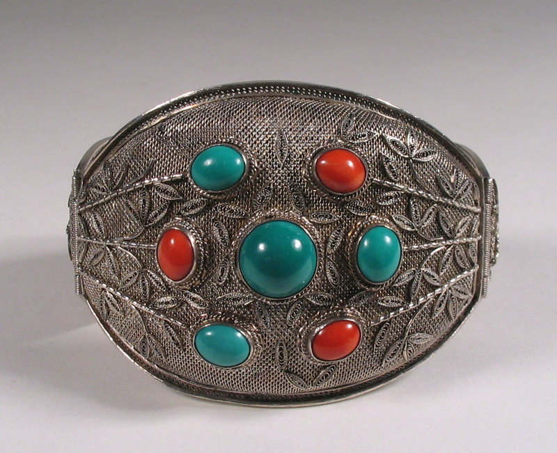 DESCRIPTION:  A lovely, large cuff bracelet crafted from a fine silver filigree mesh with a large center turquoise stone and six smaller stones of turquoise and coral. Around these are raised silver bamboo sprigs decorating the front and two hinged sides.  This bracelet is closed with a silver clasp and secured with silver chain.  Stamped "SILVER, MADE IN CHINA" on opposing plaques at the clasp.  Very good condition; c. 1920's.  DIMENSIONS: Interior circumference is 7 3/4" (19.7 cm); adult large size. <div id='rater_target1305280'></div>
