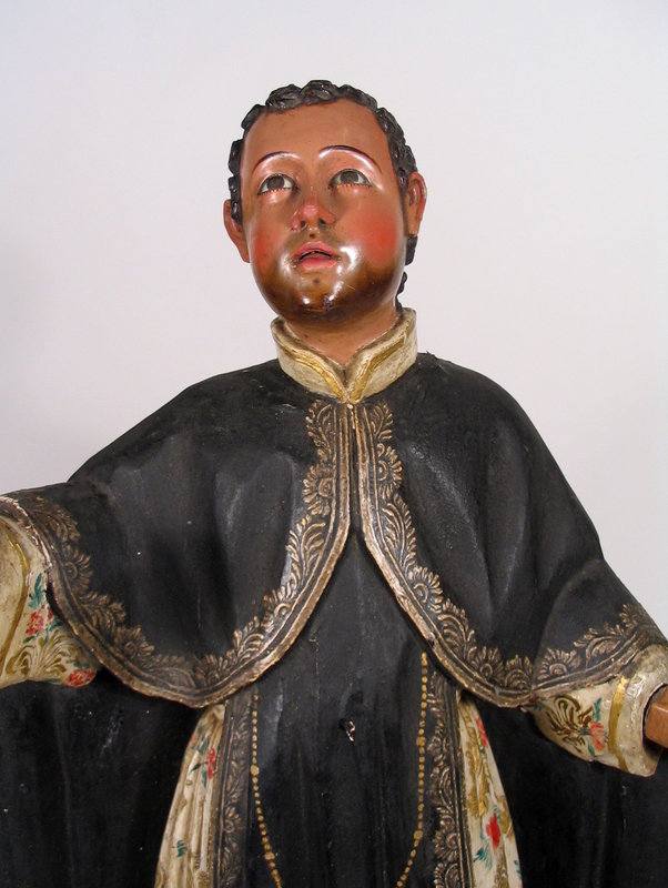 DESCRIPTION:  A large polychromed wood figure of Saint Martin De Porres, Peruvian, 18th C.  Here he is depicted gazing upward toward heaven, arms outstretched, wearing his Dominican robe embroidered in gold with a long painted rosary dangling past his waist.  His white undergarment is richly painted with flowers and gold leafy tendrils.  Carved in full round, his head is set with glass eyes and he retains a good amount of the original paint.  DIMENSIONS:  26 inches high (66 cm).
<p>SAINT MARTIN:  Martin de Porres Velázquez was born in 1579 in Lima, Peru, the son of a mixed race mother and a Spanish nobleman who eventually abandoned the family. He spent his childhood in abject poverty. At fifteen he became a lay brother of the Dominican Order in Lima and spent his whole life there as a barber, farm laborer, almoner, and infirmary worker among other things.  He maintained an austere lifestyle, even by Dominican standards, and devoted himself to ceaseless and severe penances.  St. Martin's love was all-embracing, shown equally to humans and to animals. He was noted for work on behalf of the poor, establishing an orphanage and a children's hospital, as well as an animal hospital at his sister's house.  He ministered without distinction to Spanish nobles and to the slaves recently brought from Africa.  Among the many miracles attributed to him were those of levitation, bilocation, miraculous knowledge, many miraculous and instantaneous cures, and an ability to communicate with animals.  He died on November 3, 1639, and even after his death, many miracles of healing were attributed to him.  He was eventually beatified in 1837 by Pope Gregory XVI, and canonized in 1962 by Pope John XXIII. 
<p>PROVENANCE: The Antonio Roig Ferre Collection.  A native of Humacao, Puerto Rico, Antonio Roig Ferre is a noted, well respected collector and student of ecclesiastical arts, with an affinity for Spanish Colonial works. After his service in the US Armed Forces, Antonio pursued studies in both philosophy and law at the University of Puerto Rico. However, it was his interest in theology and comparative religions which laid the foundation for his lifelong interest and pursuit of Christian art, resulting in a world-class collection and private library on the subject.  In 1996, he founded the Fundacion de Arte Sacro for the purpose of making accessible these types of items to a larger audience by loaning works from his collection to various museums and institutions including: the Museo de las Americas, Denver, Colorado, USA; the Museo de Arte de Puerto Rico; the Museo del Turabo Caguas, Puerto Rico as well as the Jesuit School of Theology at Berkley, California, just to name a few. 
<div id='rater_target1306166'></div>
