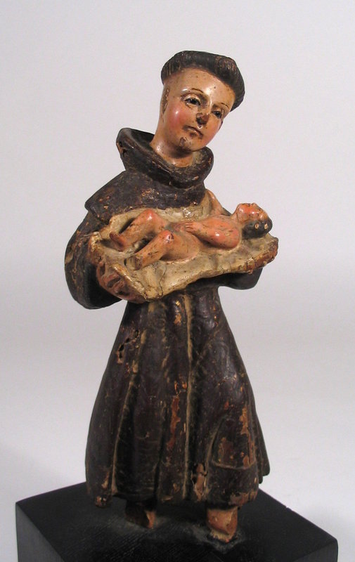 DESCRIPTION:  An engaging Spanish Colonial carved santo figure depicting Saint Anthony holding the Christ Child.  St. Anthony of Padua is perhaps one of the most loved and admired saints in the Catholic Church.  Born in Portugal in 1195, he was a Portuguese Catholic priest and friar of the Franciscan Order who later did much of his work in Italy.  Here St. Anthony  is dressed in a brown friar's habit with head tilted to one side, gently holding the Christ Child in his arms. This figure, dating from the 1700's has inset glass eyes and is mounted on a wood block. CONDITION:  Some chips to original paint, slight splitting, and areas of insect damage, all common to figures of this age.  DIMENSIONS:  12.75" high including stand (32.5 cm); stand is x 5" square (12.7 cm).  <div id='rater_target1310287'></div>
