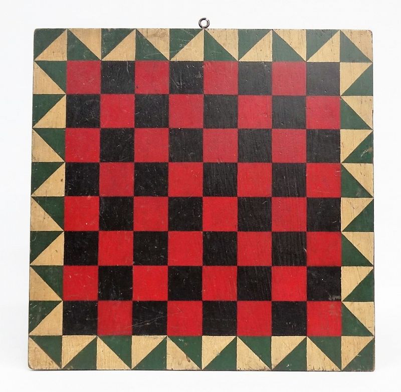 DESCRIPTION: A colorful folk art game board of alternating red and black squares for playing checkers or chess, bordered by green and white triangles, giving an overall pleasing geometric effect. An eye hook has been mounted on one edge for hanging; very good condition, C. 1900's. DIMENSIONS:  17.5” square.
<div id='rater_target1364837'></div>
