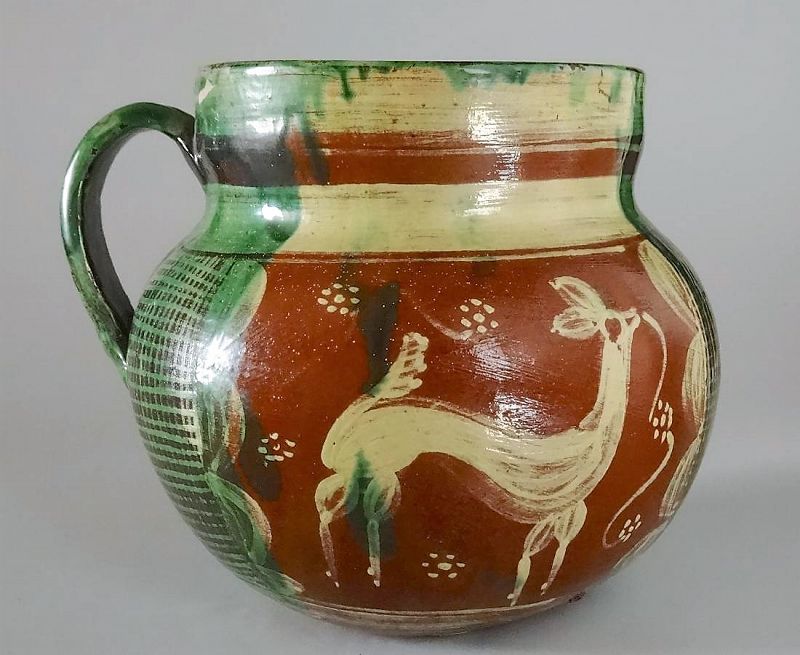 DESCRIPTION: A vintage terra cotta pitcher (or handled pot), skillfully hand-painted in green and white glazes with deer painted on each side using fluid brush strokes. Originating from the Tlaquepaque-Tonala area of Mexico, this delightful redware pitcher is in excellent condition; no chips or cracks.  DIMENSIONS: Body is 6.25” x 5.5”; 5” high.


<div id='rater_target1364930'></div>
