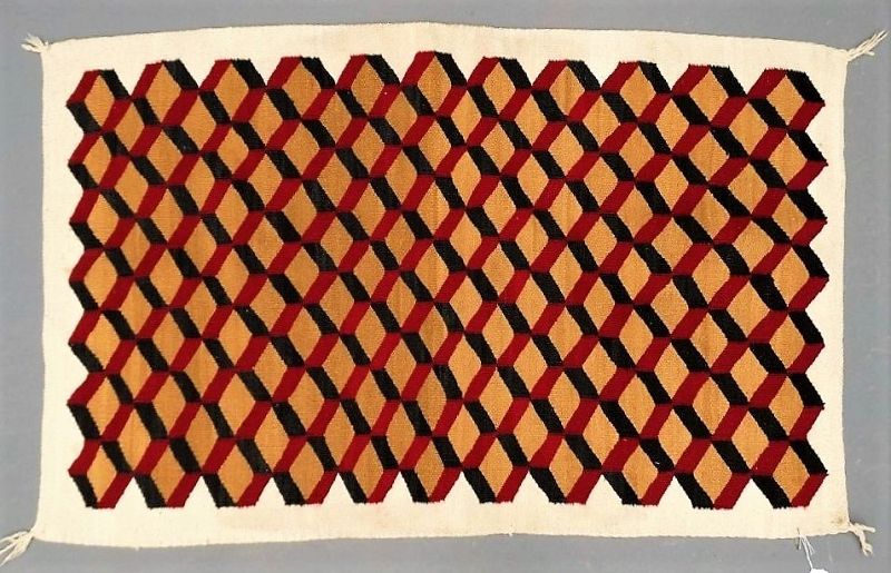 DESCRIPTION:  A hand woven Native American rug in a traditional tumbling blocks pattern, a Navajo motif also found in Americana quilts. This attractive, double sided, flat weave wool rug uses natural dyes in red, black and tan to form the block designs. Very good condition, no holes or tears. DIMENSIONS: 55” x 35".
<div id='rater_target1365857'></div>
