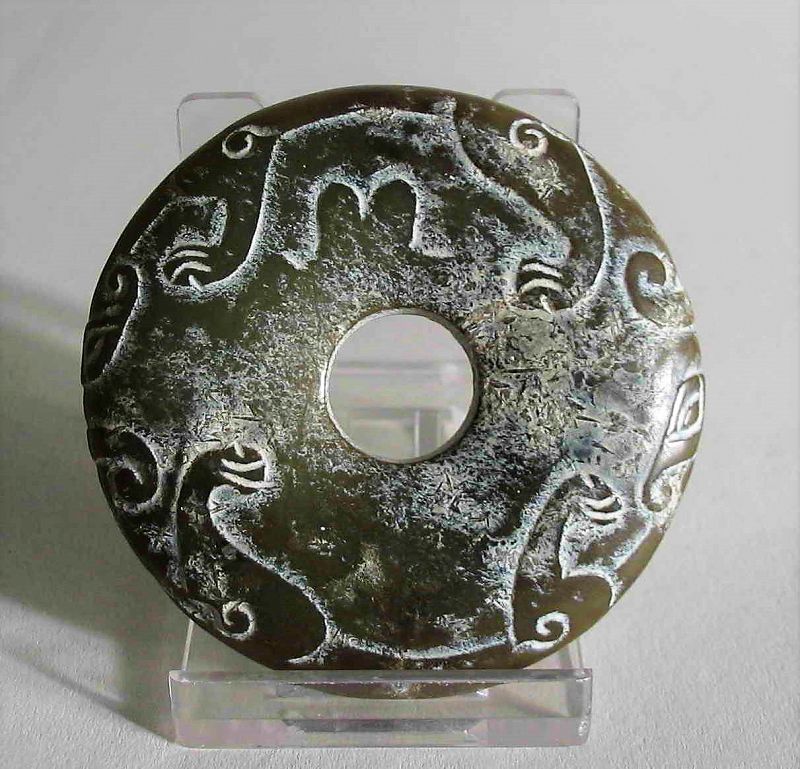 DESCRIPTION: An appealing green nephrite disk or bi, carved with two chilong dragons whose heads and bodies ring the edges with their limbs draping down on either side. From a mid-west collection, the design, color and form are quite pleasing and could be used as a toggle or an eye-catching pendant when incorporated into a necklace. DIMENSIONS: 2 5/8” diameter (6 cm), 2.25 oz. (64g) weight.   
<div id='rater_target1366422'></div>
