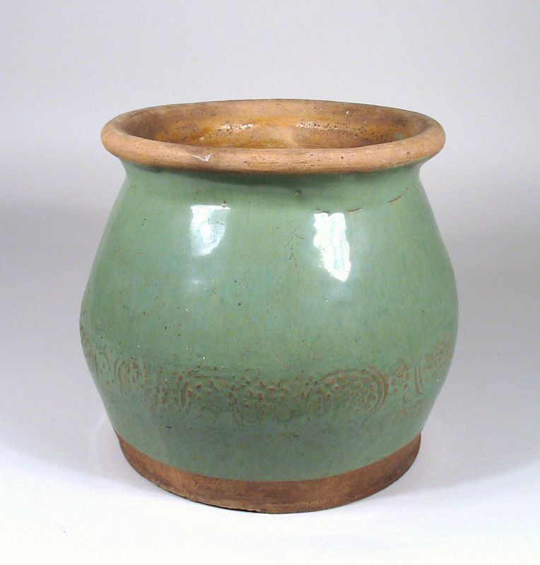 DESCRIPTION: An attractive antique Chinese stoneware jar with wide body and outward turning rim, hand crafted with a pleasing celadon glaze over a raised border of circular designs. In original firing condition and dating from the early 20th C. Though the origin is Chinese, this crock would lend a nice touch of "country" in a cottage or farmhouse setting. DIMENSIONS: 7.5” high (19 cm) x 8” diameter (20.3 cm).   
<div id='rater_target1367832'></div>
