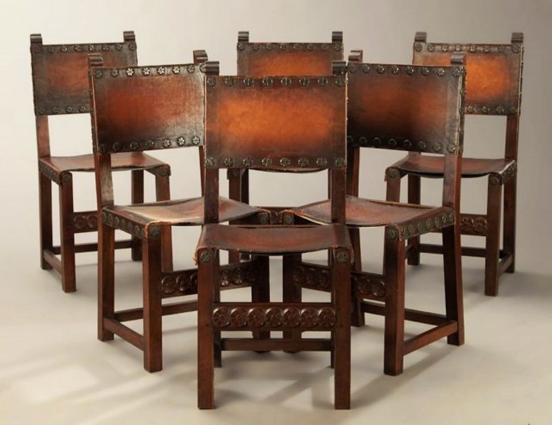 DESCRIPTION: A handsome set of six Spanish Renaissance carved walnut and leather dining chairs, 19th c., the rectangular leather backs over rectangular leather seats with large bronze floret tack trim, on square legs joined by stretchers with hand carved circular florets.  CONDITION: Condition is consistent with age and use. The wood is in good condition with minor scuffs and nicks. The leather upholstery has some mild cracking and some wear at the edges. A good looking set with considerable Spanishl old world charm.  DIMENSIONS:  37.5” high x 17” wide x 14.25” deep.  Seat height is 18”
<div id='rater_target1368887'></div>
