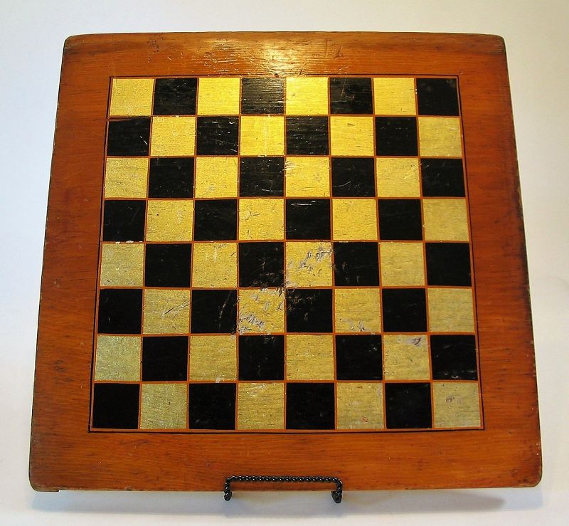 DESCRIPTION:  A good country wood game board in original paint with alternating hand painted black and metallic silver/gold squares outlined in red pin stripes.  Abrasions to area in center of board; sturdy construction.  DIMENSIONS:  15.75” square x 7/8” thick.
<div id='rater_target1369460'></div>

