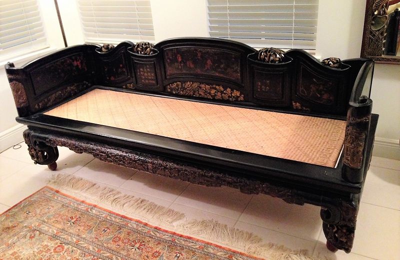 Reduced Price!<br /><br />
DESCRIPTION:  A rare and beautiful Chinese daybed or opium bed (also referred to as a lady's couch bed, lohan, or "ta" bed), the black lacquered wood back and side panels shaped as an unfurled scroll with elaborate decorations including figural scenes, animals, flowers and birds, Chinese poetry and pierced gilt carvings. These surround a rectangular support frame topped with a woven mat seat. Below the seat an elaborately carved skirt stretches between thick, boldly carved legs. <p>This well-preserved piece was once used in the scholar's studio where it was convenient for sleeping, reclining and sitting with books and scrolls spread out. Early to mid 1800's. PROVENANCE: From a long held Port St. Lucie, Florida, collection from where it will be shipped.  CONDITION:  Quite good condition with some superficial cracks to the lacquer surface; original finish, solid wood construction, hand painted and carved. Very sturdy with normal age wear. DIMENSIONS: 30"height (78 cm) × 81.5"width (208 cm) × 29"depth (75 cm).
<div id='rater_target1370834'></div>

