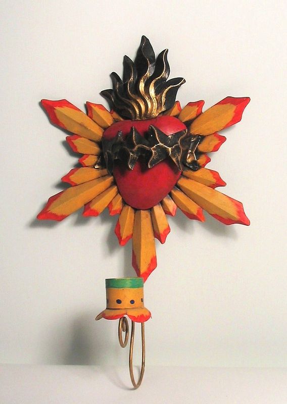 DESCRIPTION:  A painted metal devotional candle holder depicting the Sacred Heart of Christ with a yellow sunburst design behind a heart with flames and crown of thorns.  Wall mounted with hanger on reverse; very good condition; Mexican.  DIMENSIONS:  12.75” high x 9” wide.
<div id='rater_target1388720'></div>

