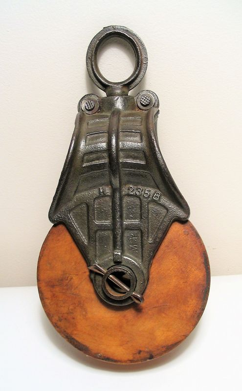 DESCRIPTION: A tribute to vintage industrial design, this attractive pulley, with a heavily cast iron shaft and swivel eye, is attached with snatch pins to a smooth, grooved wooden wheel.  The pulley is a simple machine that, when used with a rope, will reduce the amount of force needed to lift a load.  These make wonderful decorative accents within a country, farmhouse or industrial decor.  In excellent working condition, no rust. DIMENSIONS:  12” long x 6” wide.
<div id='rater_target1394688'></div>
