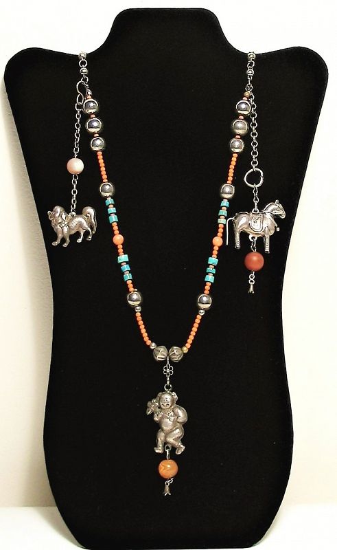 DESCRIPTION:  A beautiful antique Chinese necklace strung with pink coral, turquoise and silver beads.  Three silver figural pendants hang from the necklace, including a foo dog, a horse with saddle and bridal, and a child holding a large flower, each with agate beads. Qing Dynasty, excellent condition. DIMENSIONS:  28.5” end to end (72.5 cm).
<div id='rater_target1397130'></div>
